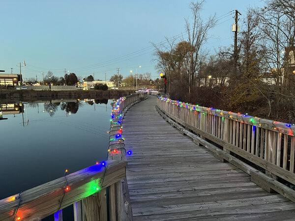 A lit boardwalk curving along the water