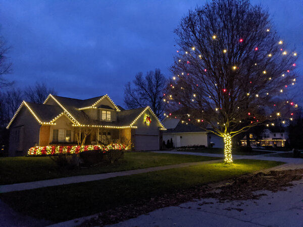 A berry-lit tree beside glowing eaves
